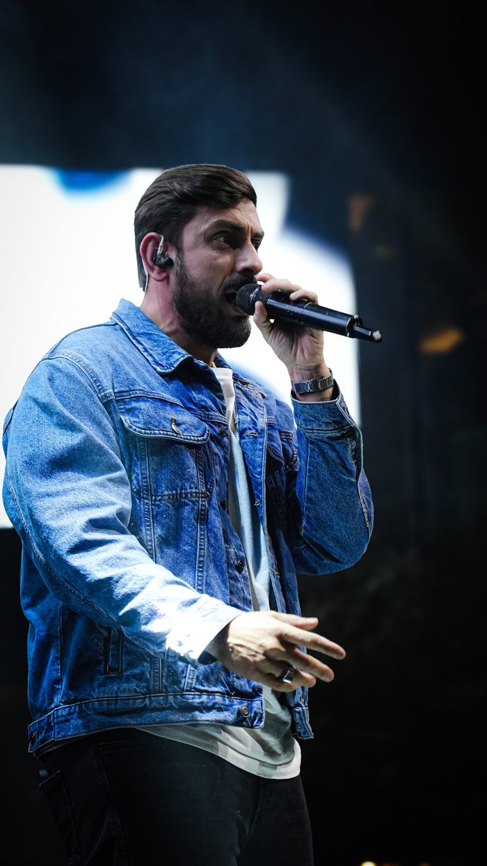 Leo Derobi no palco durante show sertanejo, cantando com a banda